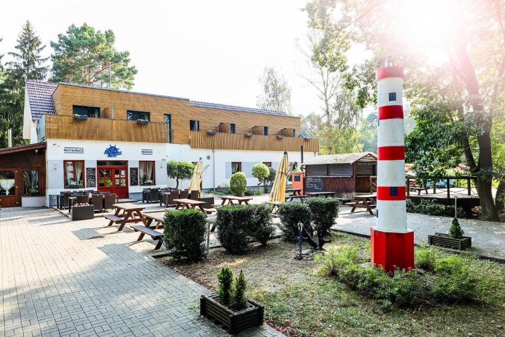 Zahrada s replikou majáku a posezením před budovou penzionu